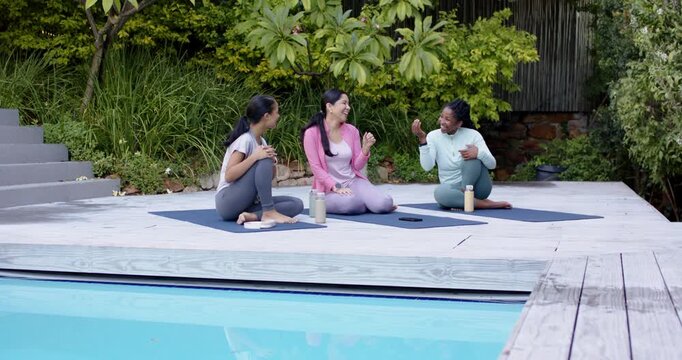 Three women reacting to right speaker starting story post-yoga poolside with blue mats and phone