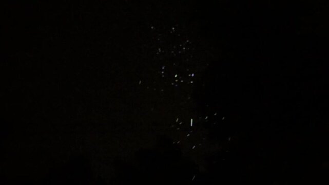 Glistening rain drops against the dark night sky time warping from regular speed to super slow motion and then back to regular speed 