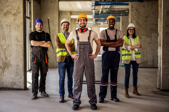 A smiling group of diverse architects and construction workers looking at the camera.