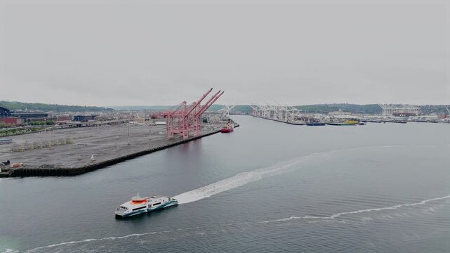 Aerial drone view of passenger ferry crossing Elliott Bay near port cranes and terminals