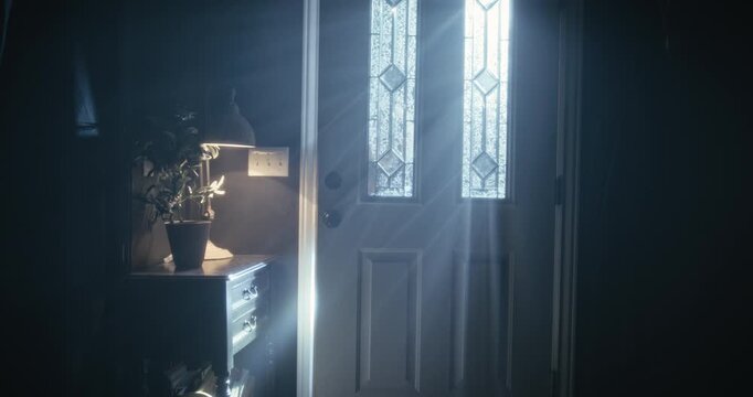 Dolly in, medium shot on lone young woman entering spooky home with flashlight as lightning flashes outside