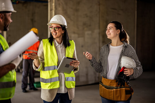 Female builder consulting with architects holding a digital tablet during renovation.
