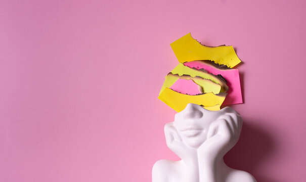 White sculpture with colorful burnt pieces of paper on a pink background