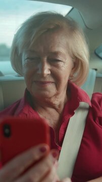 Senior lady enjoys car ride, Graceful elderly woman in red sweater observes scenery from backseat calmly