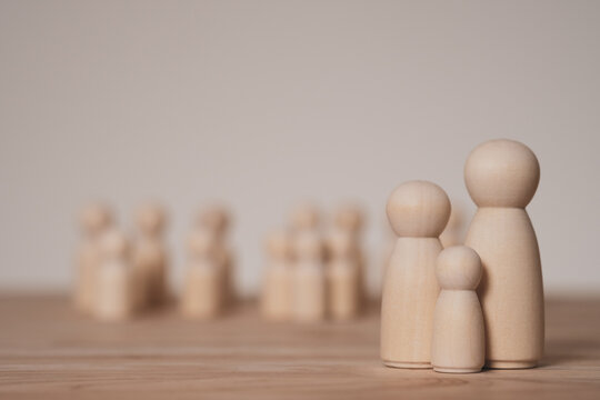 Conceptual wooden dolls forming a small family illustrating parenting responsibility, social expectations and hope parents have for their children success.