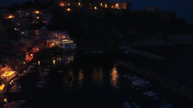 Panoramic aerial shot of Procida town glowing along