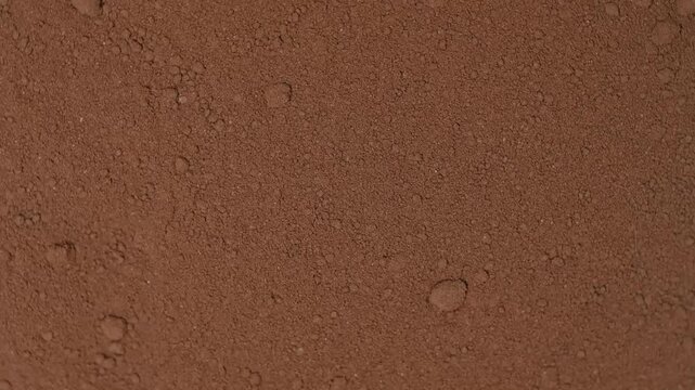 Top view macro shot of fine organic cocoa powder rotating slowly. Premium dark chocolate ingredient texture background