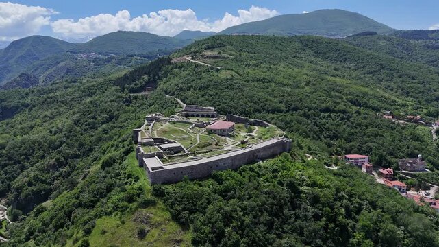 Aerial drone footage of the historic fortress of Prizren captured on a sunny day, showcasing the ancient stone walls, hilltop views, red rooftops, and the beautiful urban landscape of one of Kosovo&rsquo;s 