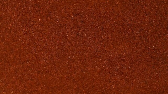 Top view macro shot of fine ground red paprika spice rotating slowly. Premium hot chili or sweet pepper powder texture background