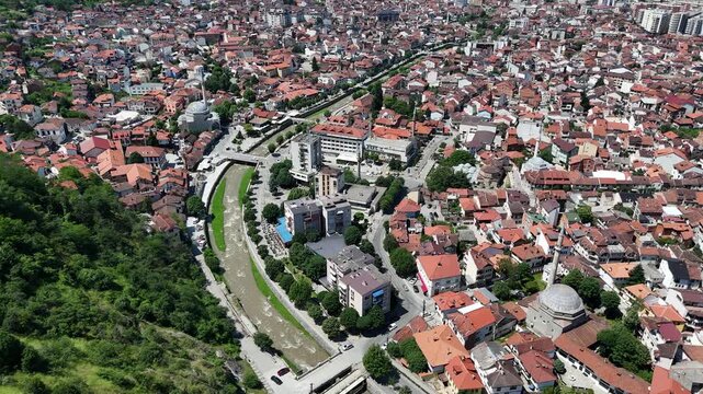 Cinematic aerial view of Prizren with the river flowing through the historic city center, captured with a drone on a bright sunny day in Kosovo.
