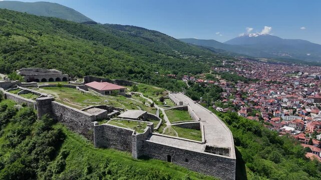 Aerial drone footage of the historic fortress of Prizren captured on a sunny day, showcasing the ancient stone walls, hilltop views, red rooftops, and the beautiful urban landscape of one of Kosovo&rsquo;s 