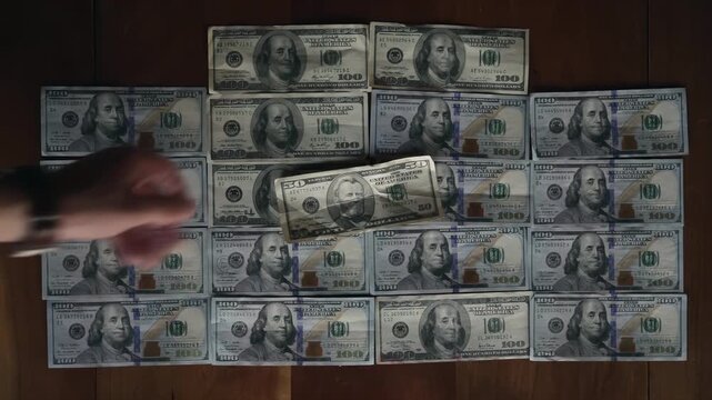 Stacks of hundred dollar bills arranged neatly on a wooden surface for financial concepts