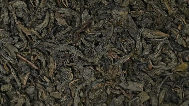 Top view macro shot of loose-leaf green tea rotating slowly. High quality dried gunpowder or sencha tea texture background