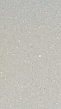 Top view macro shot of white refined sugar crystals rotating slowly. High quality sweet ingredient texture background