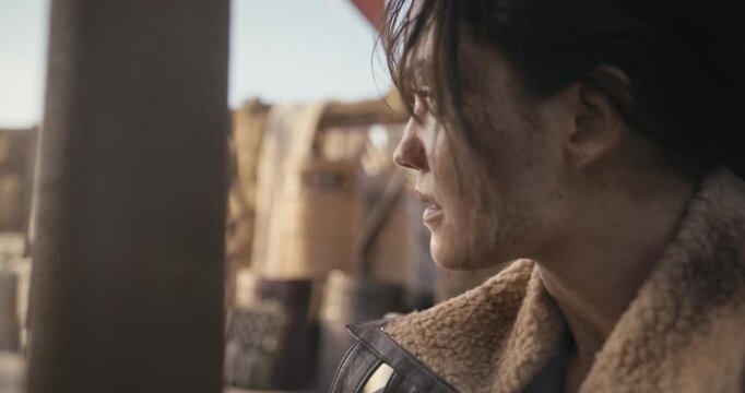Steady cam closeup shot of silhouetted young woman covered in dirt and captive in sci-fi desert