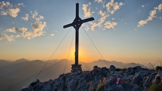 Gipfelkreuz im Sonnenuntergang mit Blick in die Bayerischen Voralpen