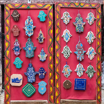 Colorful hamsa charms displayed on a red market board