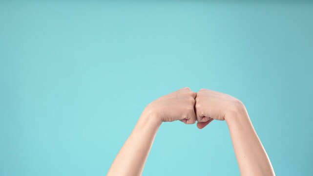 Close up of two hands doing a fist bump gesture on blue background