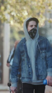 Selfassured teenager in layered clothing gets ready to skate along city sidewalks amid autumn scenery