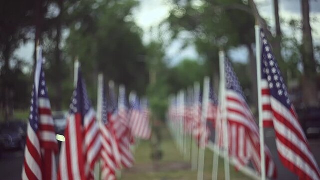 Slow motion cinematic footage of a row of American Flags Lining a Suburban Street with Bokeh Background and copy space