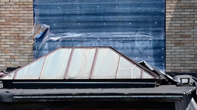  rundown building rooftop showing blue tarp waving in the wind