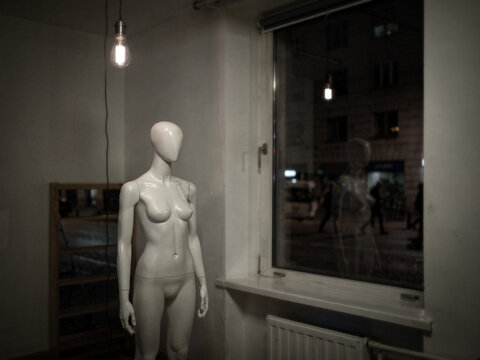 A naked mannequin stands alone in a derelict shop highlighting the concept of declining high street retail