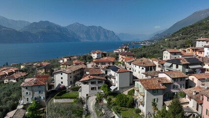 Fototapeta premium Beautiful Italian village captured by drone at sunset over Lake Garda. Peaceful atmosphere with boats on the water and scenic lakeside landscape.
