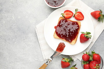Fototapeta premium Toasted bread with strawberry jam and fresh berries on light grey table, flat lay. Space for text