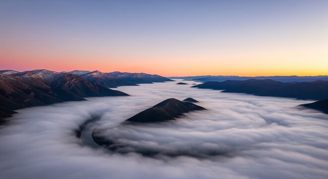 Mountain peaks rising above thick clouds at colorful dawn