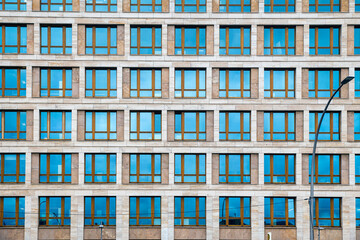 Obraz premium A straight-on, flat lay style architectural photograph of a large building facade made of light beige stone tiles. The facade 