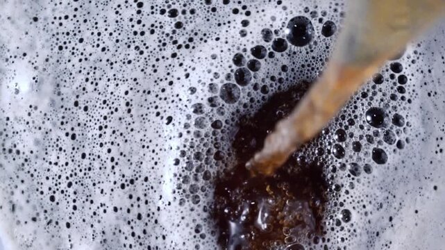 Top Down View of Amber Beer Pouring into Thick White Foam 
