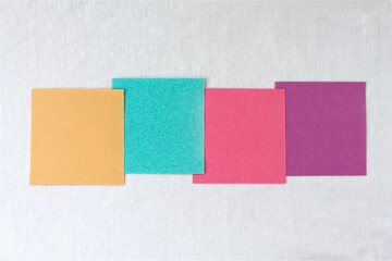 Fototapeta premium Four colorful blank sticky notes in a row on white linen background with copy space, multicolored paper options template.