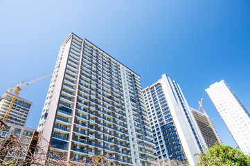 Obraz premium High-rise building under construction with tower crane against a clear blue sky.
