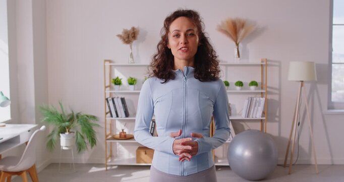 Portrait of woman trainer and fitness blogger records online training video at home, engaging in sport communication with focus on workout in a personal setting with dedication and energy.