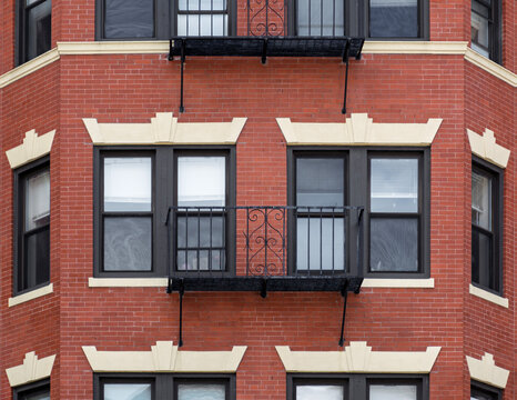 Historic red brick apartment building with black metal Juliet balcony and stone lintels in Boston, Massachusetts, USA