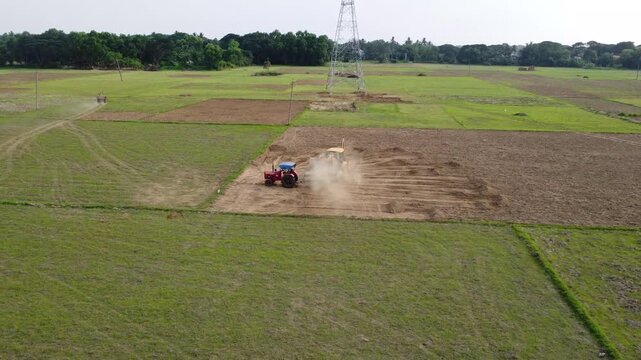 Drone Footage of Farm Tractors and Excavator Preparing Ground Near Power Pylon Infrastructure. Excavator Loading Earth into Tractor Trailer.