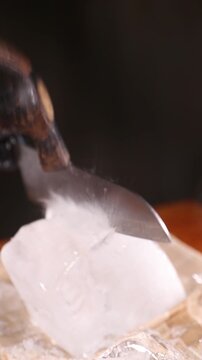Barman cortando un bloque de hielo con cuchillo y martillo. Barman cortando un bloque de hielo con cuchillo y martillo.