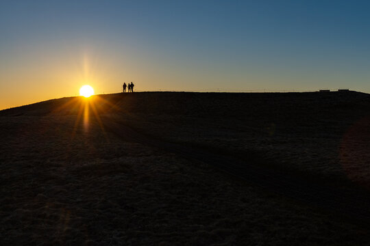 Silhouettes de randonneurs admirant le coucher du soleil sur une colline
