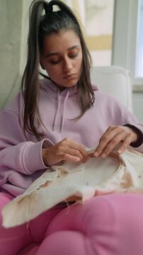 Young lady mend fabric with embroidery in cozy room setting