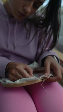 Person diligently performing detailed embroidery with concentrated effort