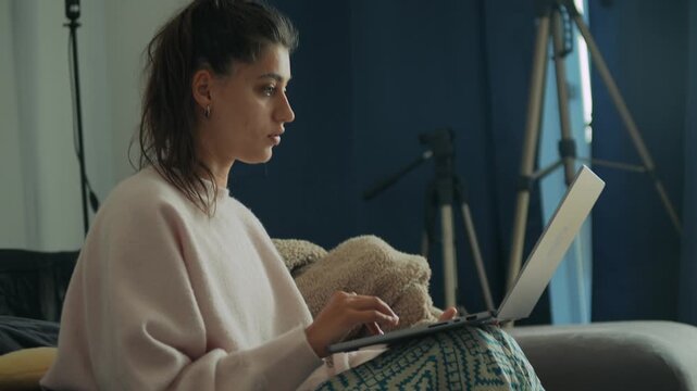 Relaxed woman using laptop amidst filming and editing tools