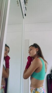 Woman in sportswear checks posture and expression in bright room