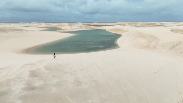 Cinematic woman exploring Len&ccedil;&oacute;is Maranhenses National Park in a lagoon landscape
