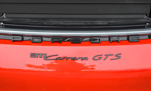 This close up highlights the bold, black lettering of the Porsche 911 Carrera GTS emblem against its vibrant red paint, showcasing the sleek branding