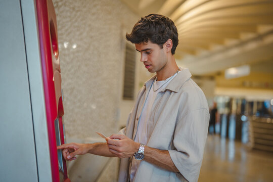 Young man using ticket vending machine at subway station