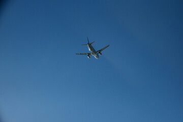 Obraz premium White Commercial Jet Airliner Flying Away Into the Clear Blue Sky