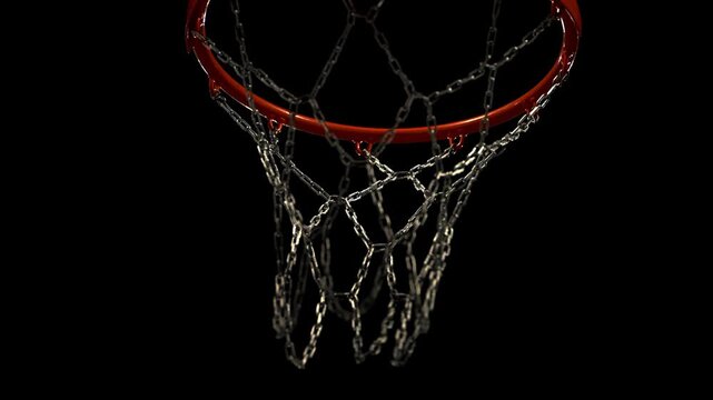 Basketball successfully passing through a metal hoop with chain net in dramatic low-light conditions. Dynamic sports action captured in close-up, highlighting precision, competition, scoring moments.