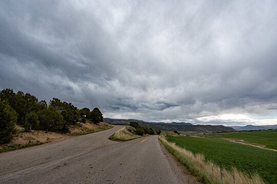 Much needed rain over agricultural fields of Grass Valley in Garfield County in western Colorado under developing storm clouds.