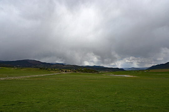 Much needed rain over agricultural fields of Grass Valley in Garfield County in western Colorado under developing storm clouds.