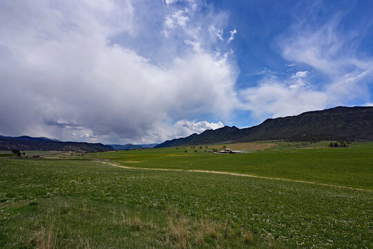 Much needed rain over agricultural fields of Grass Valley in Garfield County in western Colorado under developing storm clouds.